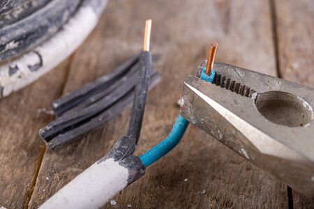 Old copper electric wire and combination pliers. Electrical installation repair. Dark background.の写真素材