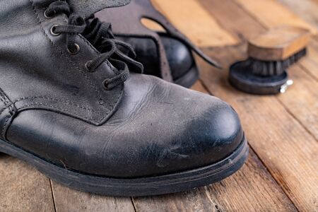 Polishing of military boots on a wooden table. Maintenance and protection of leather shoes. Dark background.の写真素材