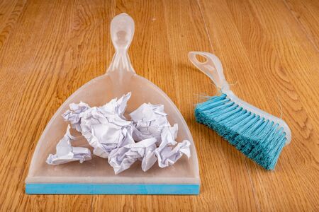 Plastic dustpan and brush on a wooden floor. Sweeping the rubbish at home. Dark background.の写真素材