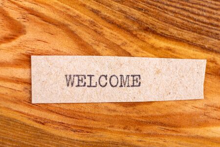 The word "welcome" typed. The inscription on a gray sheet of pappier. Wood texture background.の写真素材