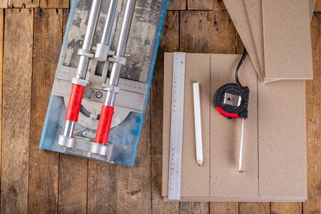 Cutting tiles in a home workshop. Tiling work on a workshop table. Dark background.