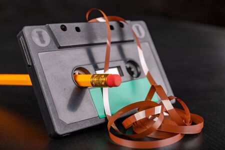 Winding magnetic tape in a cassette tape. Old methods of rewinding music tapes. Dark background.