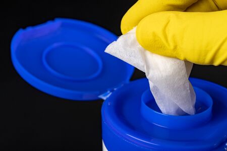 A wet cleaning cloth in a plastic container. Pulling a handkerchief out of the container. Dark...