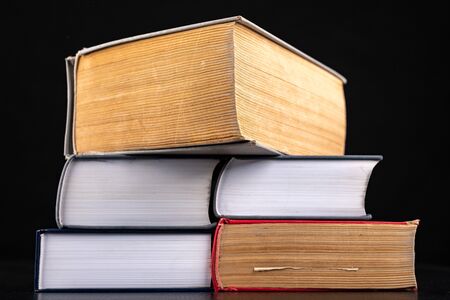 A pile of very thick and voluminous books. Enormous amount of knowledge in stacked books. Dark...