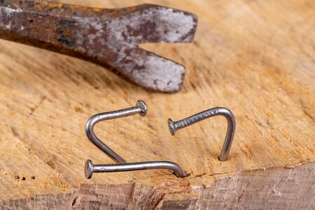 Extracting old nails from a piece of raw wood. Carpentry work in the workshop. Dark background.の写真素材