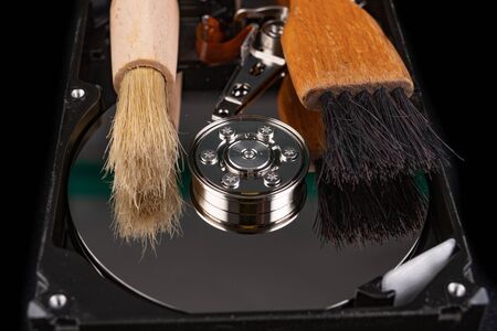 Cleaning the hard disk with a brush. Vacuuming old disk data on your computer. Dark background.