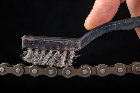 Bicycle chain and metal brush for cleaning dirt. Care of the bicycle's drive system. Dark...