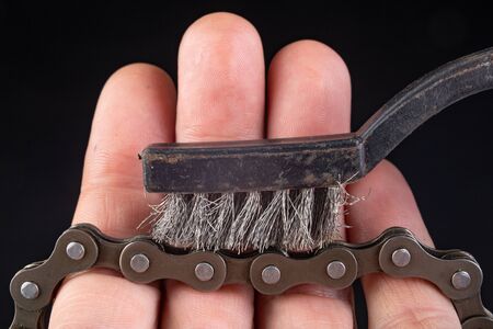 Bicycle chain and metal brush for cleaning dirt. Care of the bicycle's drive system. Dark...