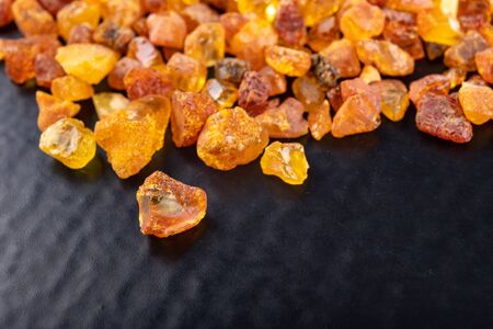 Small amber stones on a dark table. A pile of small ambers found on the Baltic beach. Black background.の写真素材