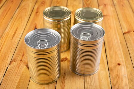 Can of cans on a kitchen wooden table. Preserved food in the household. Light background.