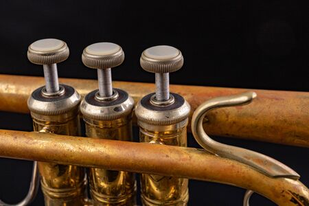 Details of an old patina covered trumpet. Musical instrument shown in magnification. Dark...