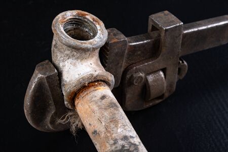 Old dirty pipe and hydraulic wrench. Accessories and tools for a plumber. Dark background.の写真素材