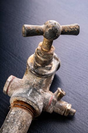 Old dirty metal water tap. Accessories and tools for a plumber. Dark background.の写真素材