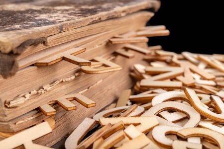Old book and wooden letters. Wooden letters spilling out of the book. Dark background.