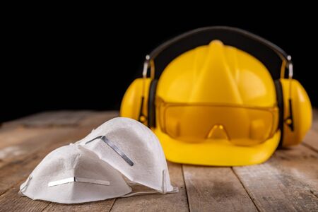 Workwear and protective mask on a wooden table. Protective accessories for the production worker....