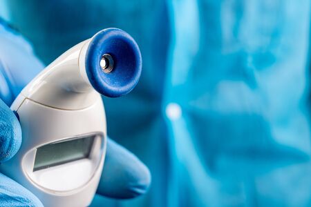 Thermometer held in the hands of a doctor. Medical accessories for diagnosis. Light background.