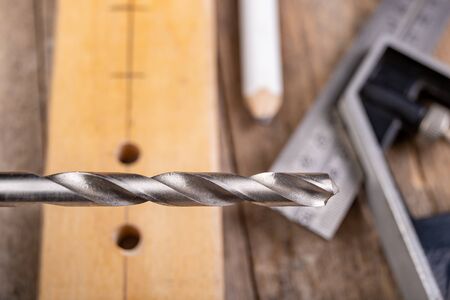 Drilling in a piece of wood with a metal drill bit. Small carpentry work in a home workshop. Light...