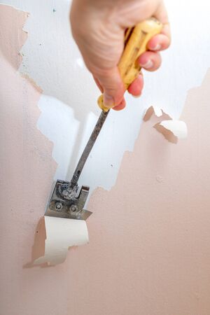Peeling old latex paint off the wall. Using a scraper to renovate a bathroom. Place - renovation at home.の写真素材