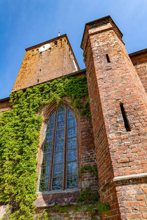 Darlowo, zachodniopomorskie / Poland - June, 4, 2020: Catholic temple in a small town in Pomerania. Old red brick building. Spring season.のeditorial素材