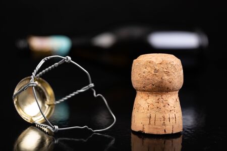 Champagne cork on a dark table. Metal basket and bottle stopper with alcoholic liquor. Black background.の写真素材