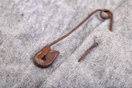 An old rusty safety pin for tailoring works in gray fabric. Accessories needed for sewing in a sewing room. White background.の写真素材