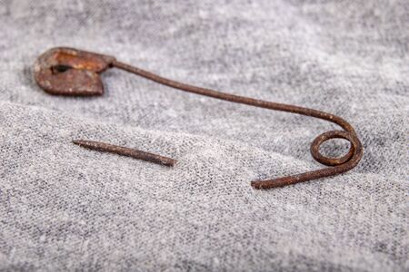 An old rusty safety pin for tailoring works in gray fabric. Accessories needed for sewing in a sewing room. White background.の写真素材