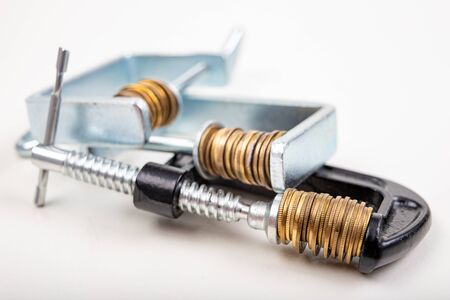 Coins squeezed in a carpenter's clamp. The image of the European currency in crisis. White background.の写真素材