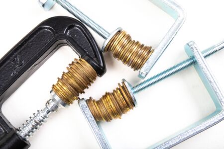 Coins squeezed in a carpenter's clamp. The image of the European currency in crisis. White background.の写真素材