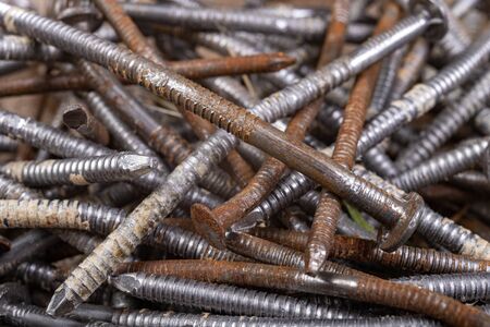 A pile of rusty nails. Old metal elements in a home workshop. Dark background.の写真素材