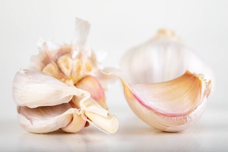A whole head of garlic and a few cloves of garlic. Vegetables used in home cooking. Light background.の写真素材