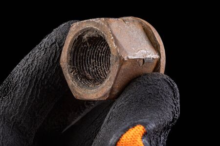 An old truck wheel bolt in hand. Truck chassis repair accessories. Workplace workshop.の写真素材