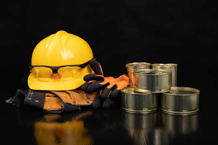 Metal cans with food. Work clothes and food for the production worker. Dark background.