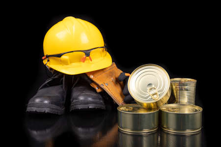 Metal cans with food. Work clothes and food for the production worker. Dark background.