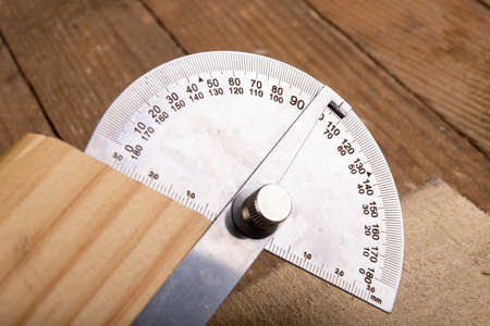 Metal protractor for measuring in carpentry. Minor work in a home workshop. Place of work back.の写真素材