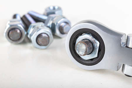 Metal bolts, nuts and a wrench for tightening. Accessories for mounting metal elements. Light background.の写真素材