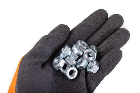 Metal nuts placed on the palm of a working glove. Accessories for mounting metal elements. Light background.の写真素材