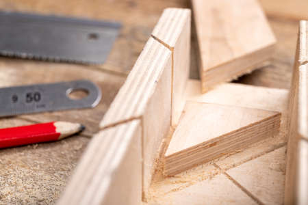 Cutting boards with a handsaw at an angle in the template. Minor carpentry work in the workshop. Light background.の写真素材