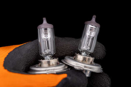 Blown bulbs on a man's gloved hand. Replaceable car accessories for headlights. Dark background.の写真素材