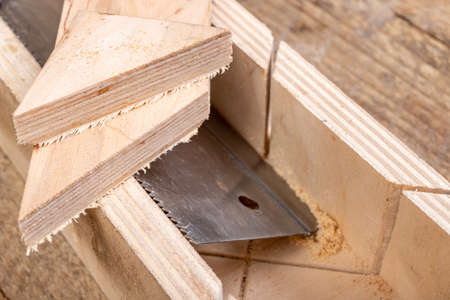 Cutting boards with a handsaw at an angle in the template. Minor carpentry work in the workshop. Light background.の写真素材