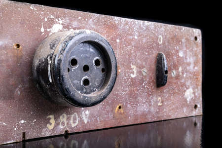 Old high voltage electric socket. Electric board with a controller. Dark background.の写真素材