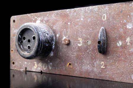 Old high voltage electric socket. Electric board with a controller. Dark background.の写真素材