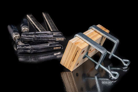 Bonding two pieces of raw plywood in carpentry clamps. Minor carpentry work in a home workshop. Dark background.の写真素材
