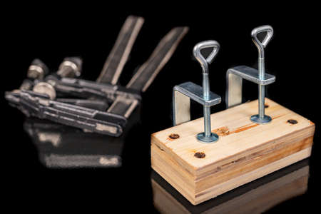 Bonding two pieces of raw plywood in carpentry clamps. Minor carpentry work in a home workshop. Dark background.の写真素材
