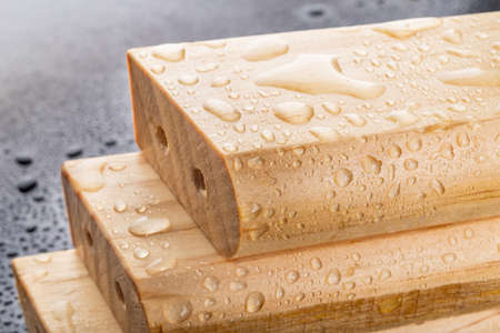 Wet wood processed and varnished in a carpentry shop. Ready-made elements for furniture assembly. Dark background.の写真素材