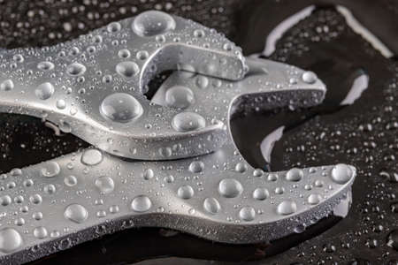 A wrench for loosening the screws. Wet tools in a car repair shop. Dark background.の写真素材