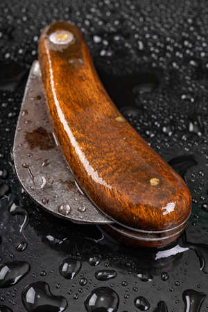 Wet knife used for gardening. Garden tools covered with drops of water. Dark background.の写真素材