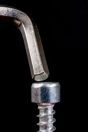 Allen screws and wrench on a dark table. Accessories for assembling furniture at home. Black background.の写真素材