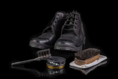 Polishing and cleaning leather shoes with a brush. Cleaning work shoes. Dark background.の写真素材