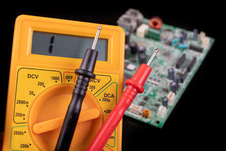 Voltmeter and circuit board. Measurements and repairs in an electronics workshop. Dark background.の写真素材
