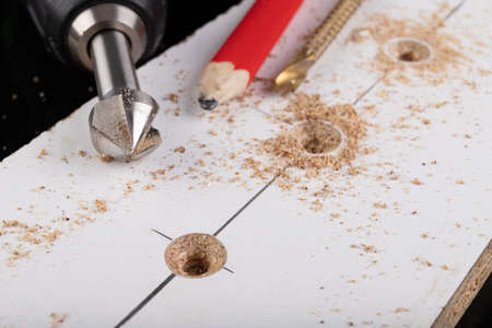 Metal countersink for making holes for screws. Minor jobs in the carpentry workshop. Light background.の写真素材